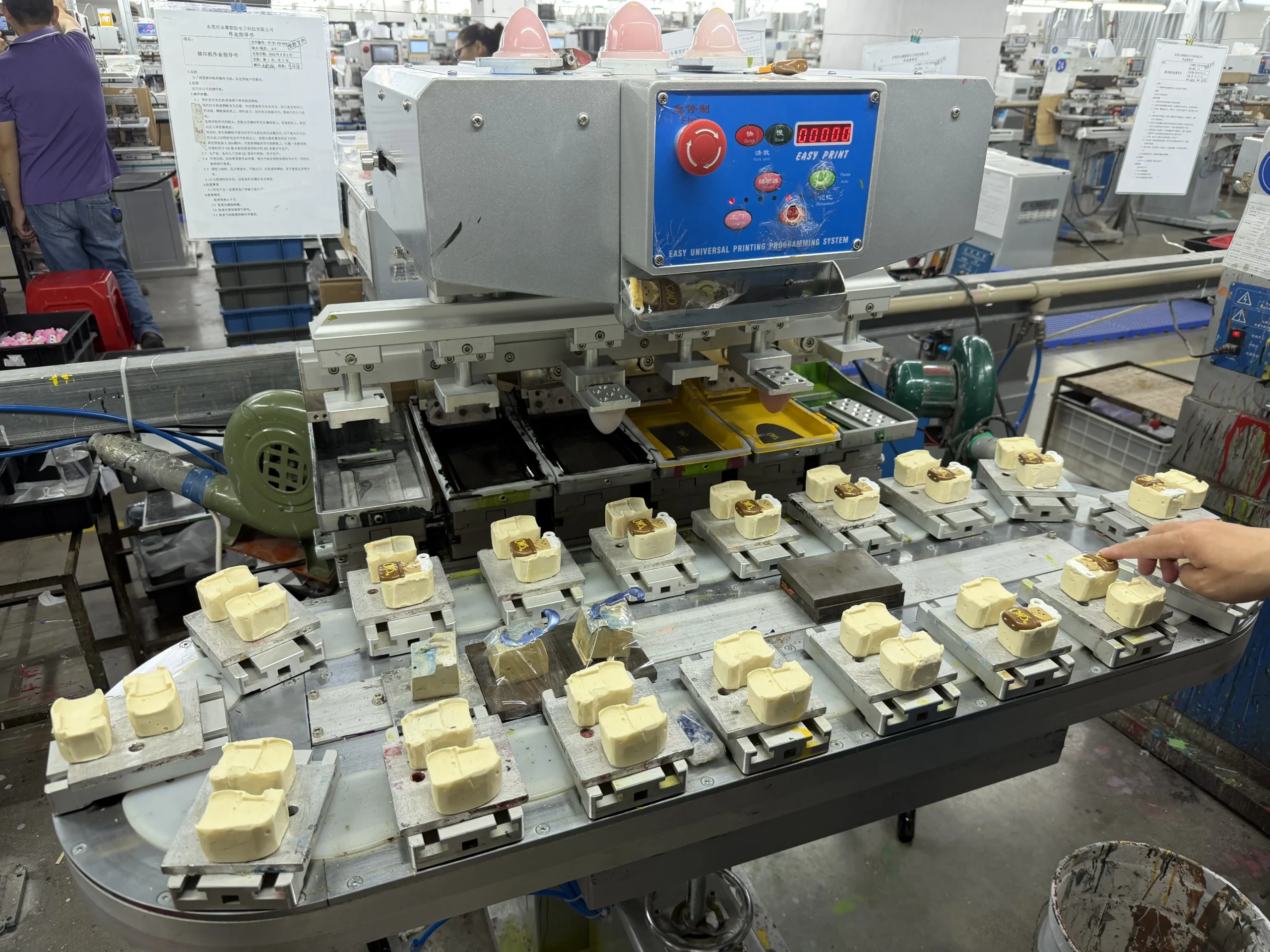 Pad printing machine applying color to custom PVC toy parts