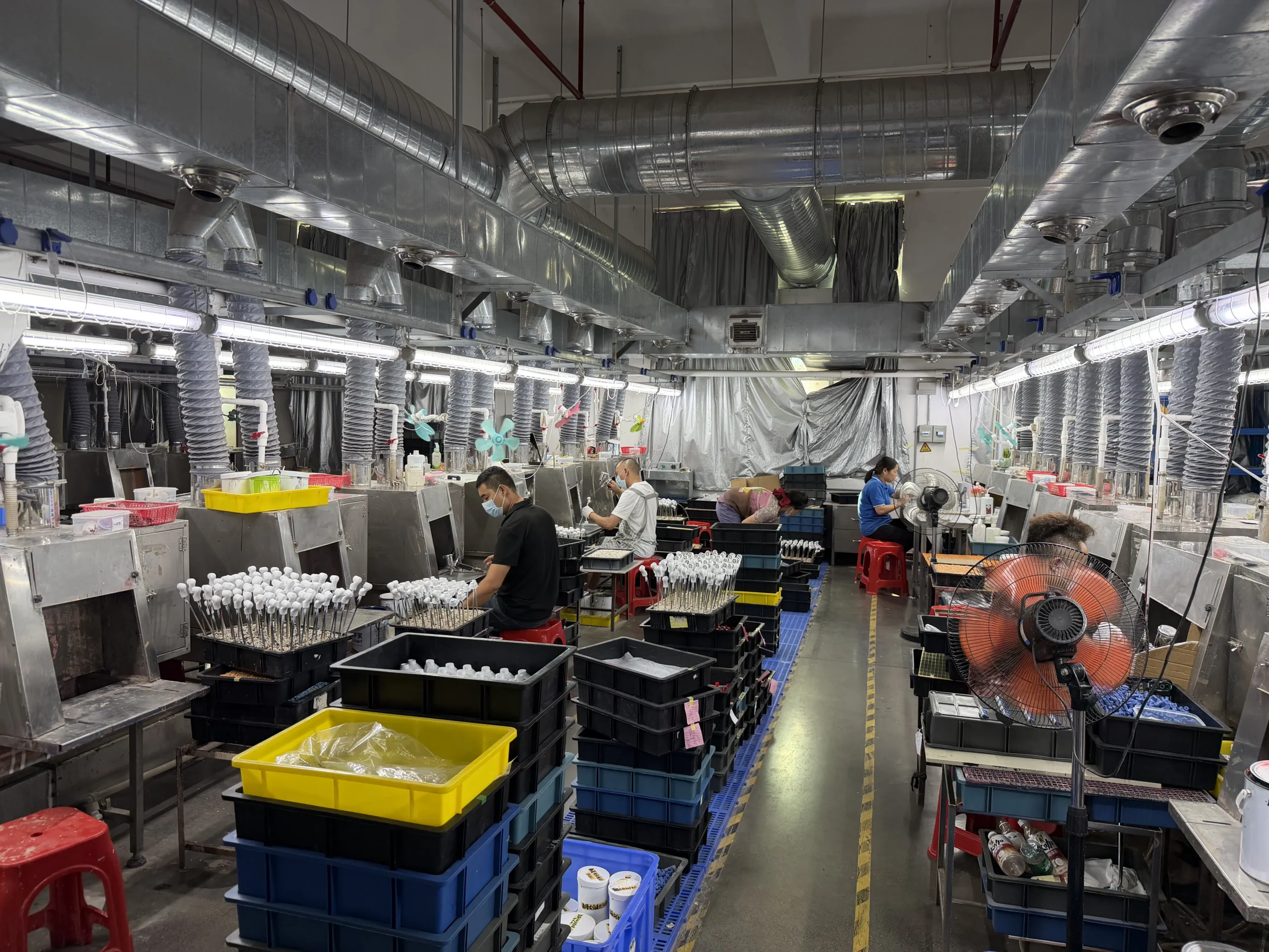 Workers painting custom PVC toy parts in the resin workshop